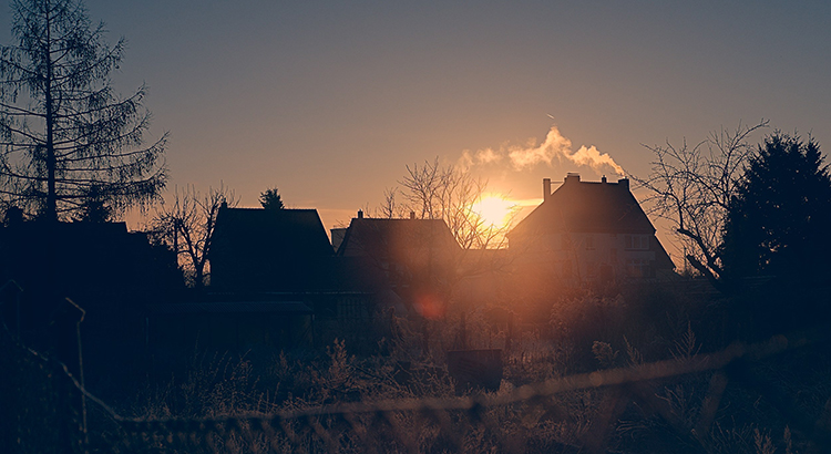 sunset with homes and trees in silhouette 