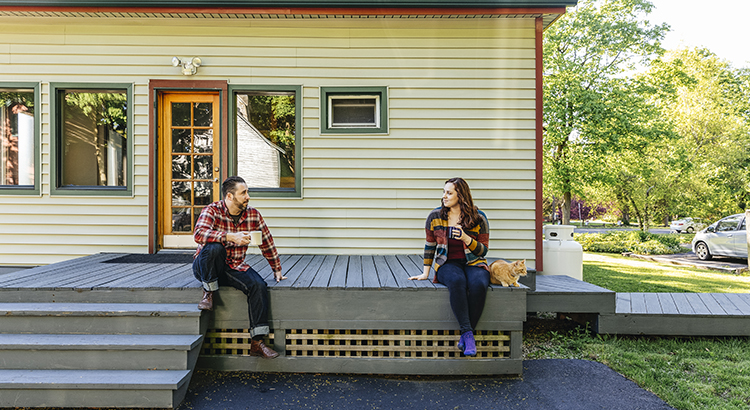 Two people talking on a home porch with coffee