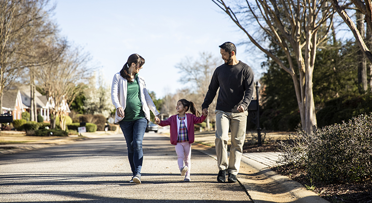 Picture of a family walking down the street in the neighborhood where they own their own home and are enjoying the equity gains of the real estate market.